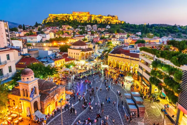 Monastiraki Square in Athens at dusk with the Acropolis lit up above the old town