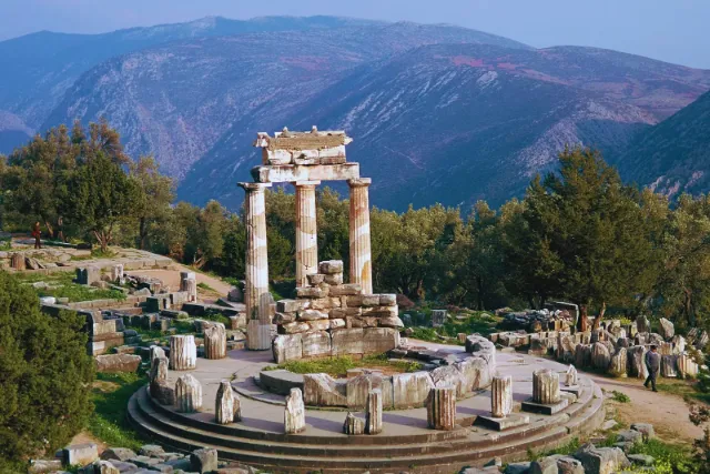 The round Tholos at the Sanctuary of Athena Pronaia in Delphi with the mountains behind it