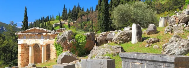 The Treasury of the Athenians among olive trees and cypresses on the slope at Delphi